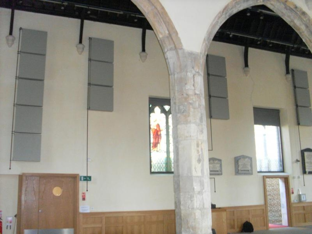 Ein Raum mit gewölbter Architektur und grauen Akustikpaneelen an den Wänden.