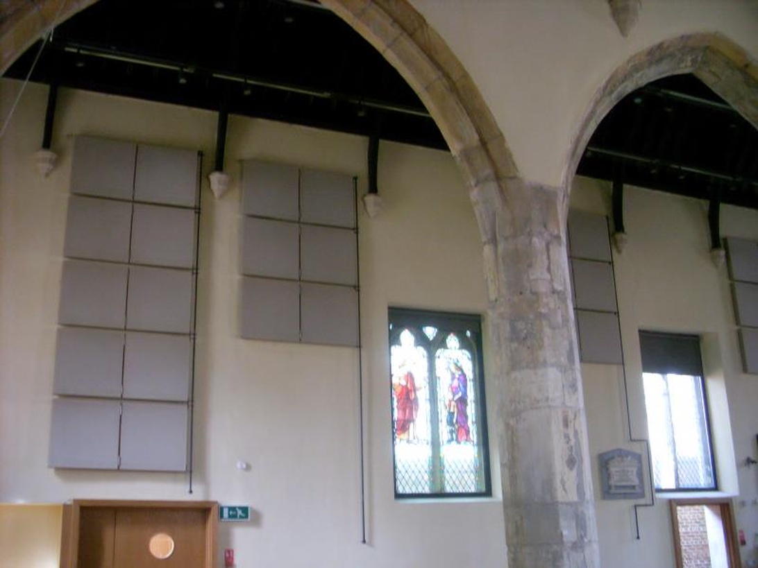 Eine weitere Ansicht des Raumes mit Bogenarchitektur, die graue Akustikpaneele zur Schallabsorption zeigt.