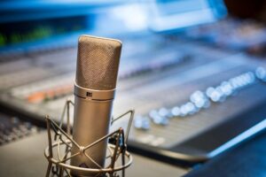 Großmembran-Mikrofon vor einem unscharfen Audiomischpult im Studio