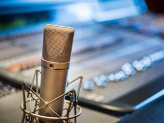 Großmembran-Mikrofon vor einem unscharfen Audiomischpult im Studio
