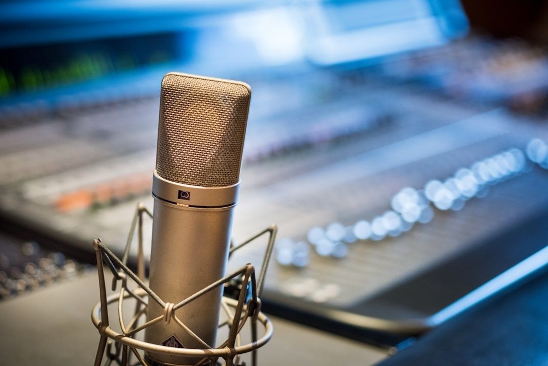 Großmembran-Mikrofon vor einem unscharfen Audiomischpult im Studio